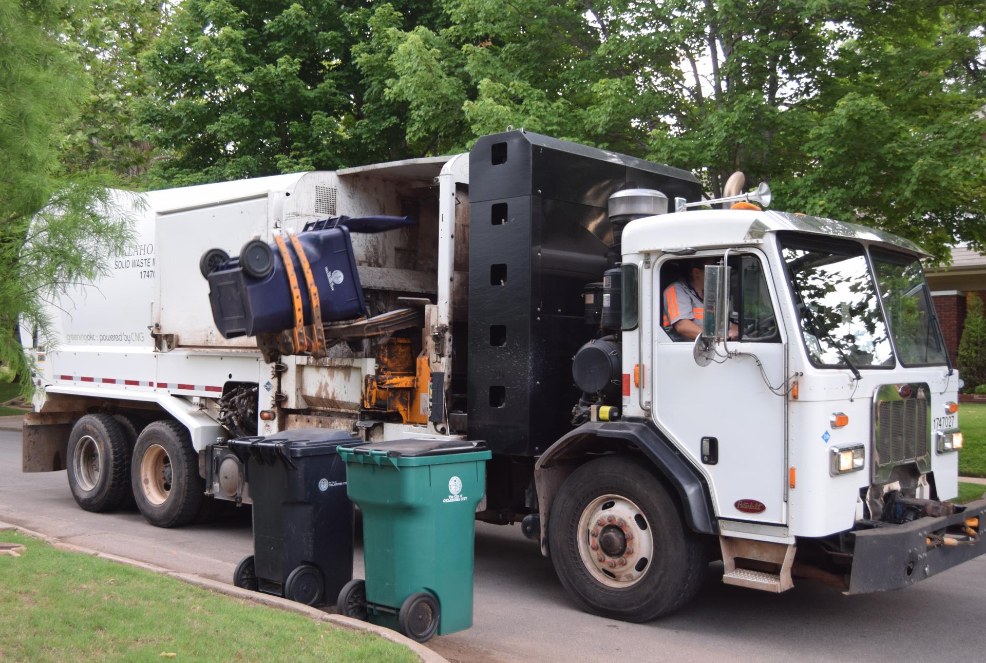 An OKC trash truck picks up a Big Blue trash cart in a local neighborhood.